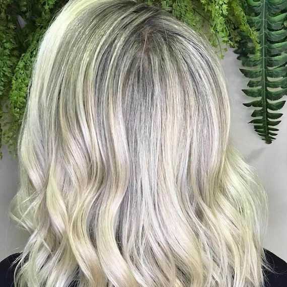 Back of the head of a woman with blonde highlights on gray roots, created with Wella Professionals.