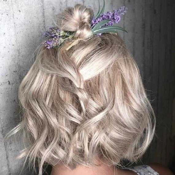 Photo of the back of a woman’s head with hair styled half-up wedding hairstyle that’s decorated with flowers, created using Wella Professionals